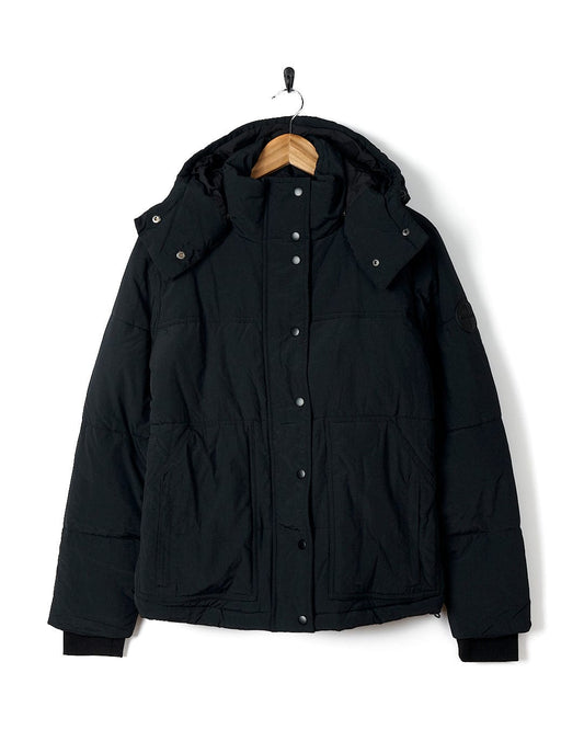 A Saltrock - Womens Short Puffer Jacket - Black with a detachable hood hanging on a hanger.