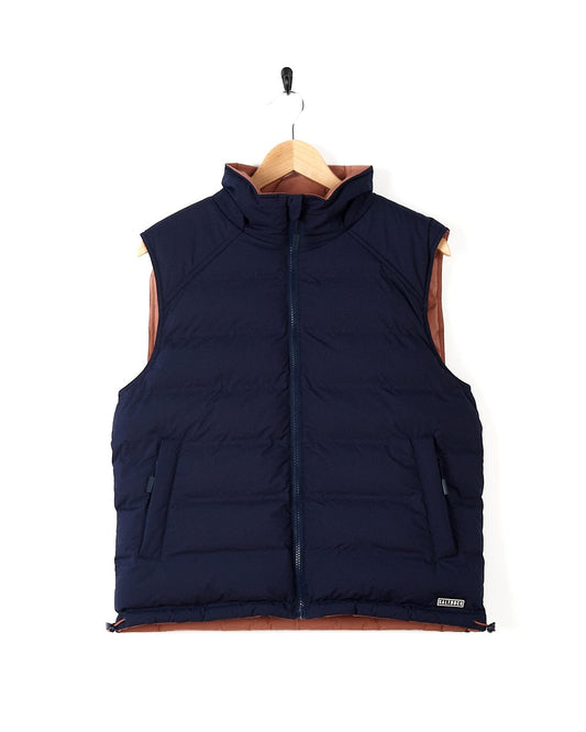 Description: A reversible navy down vest hanging on a hanger, the Saltrock Astra - Womens Reversible Padded Gilet - Blue/Pink.
