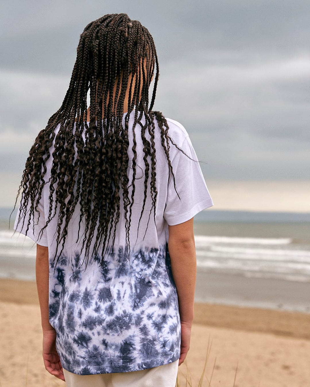 A girl wearing an Astra - Womens Short Sleeve T-Shirt - White from Saltrock standing on a beach.