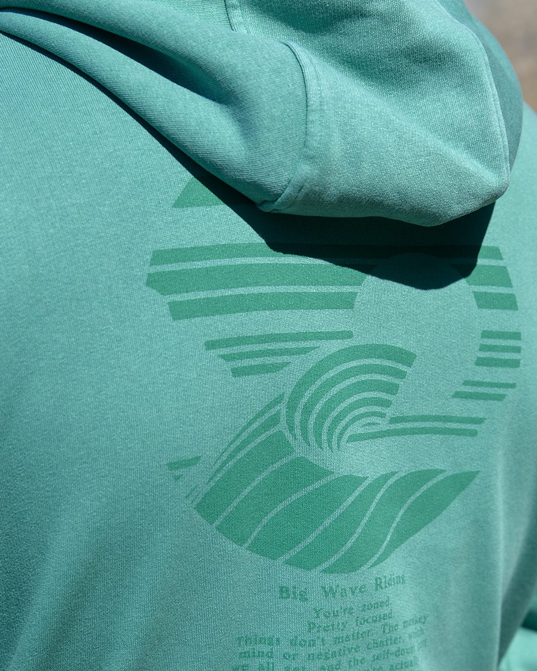 A man wearing a Saltrock Atlantic - Mens Pop Hoodie - Dark Green with a wave on it.