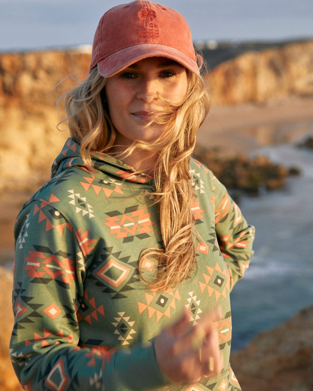 A woman wearing a Saltrock Aztec Santano Womens Pop Hoodie - Green/Orange and hat made of cotton.