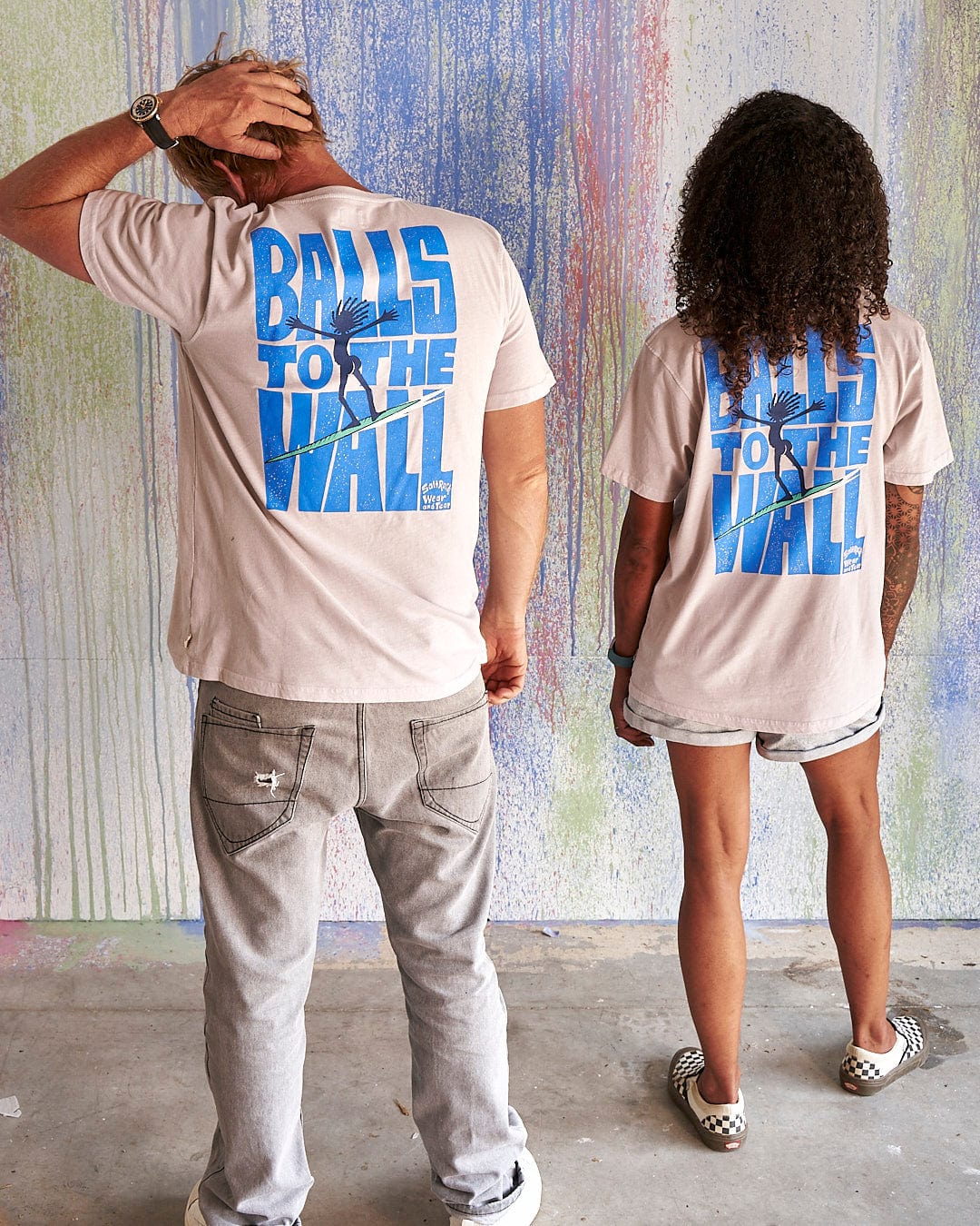 Two people standing next to each other wearing Saltrock t-shirts that say Balls To The Wall - Limited Edition 35 Years T-Shirt.