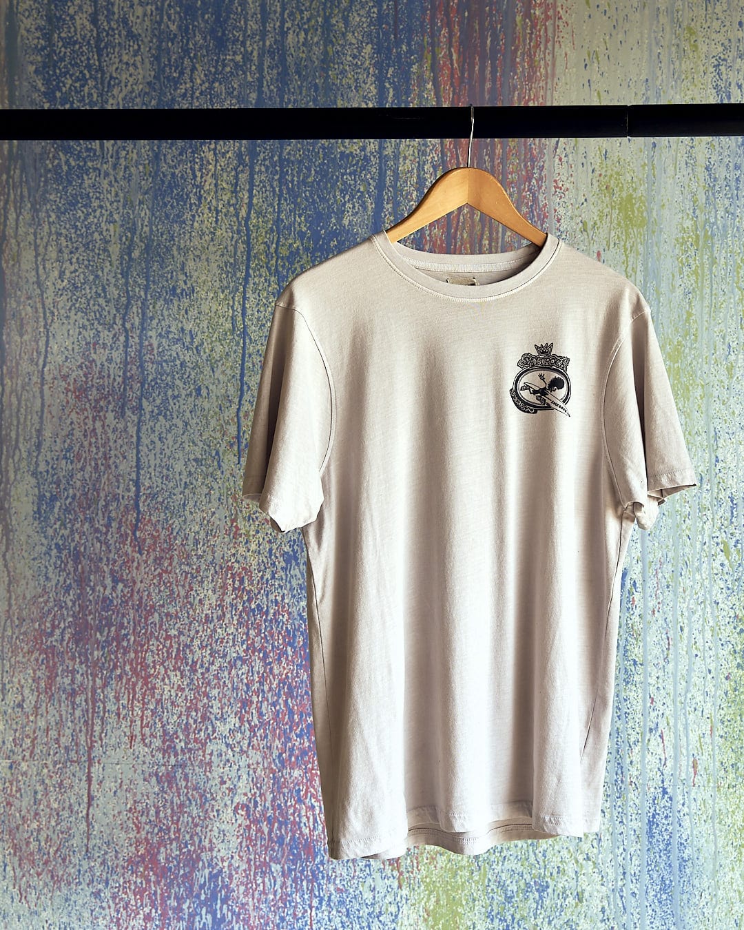 A Balls To The Wall - Limited Edition 35 Years T-Shirt hanging on a hanger next to a colorful wall. (Saltrock)