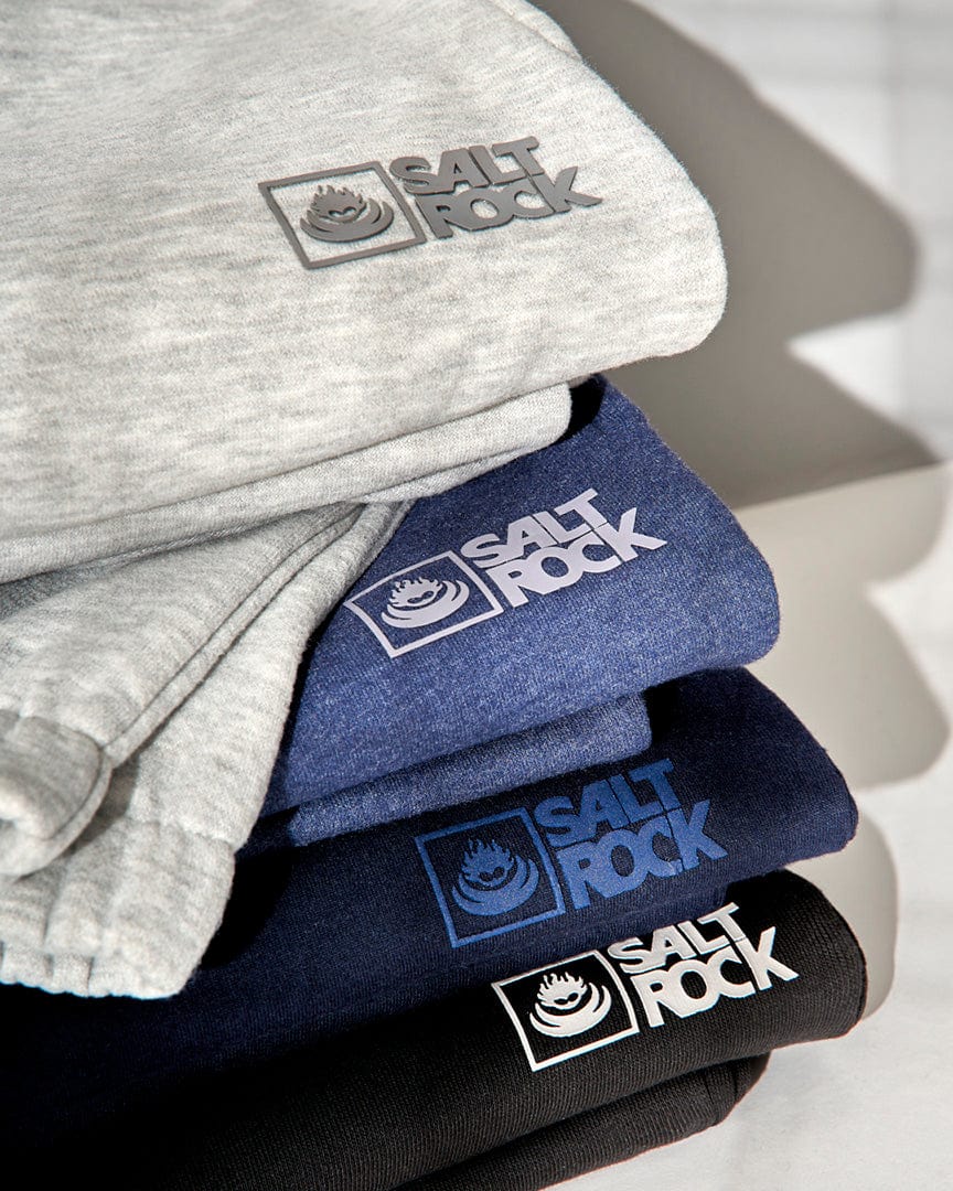Stack of folded Saltrock Original - Mens Joggers in grey, blue, and black, made from soft jersey material.