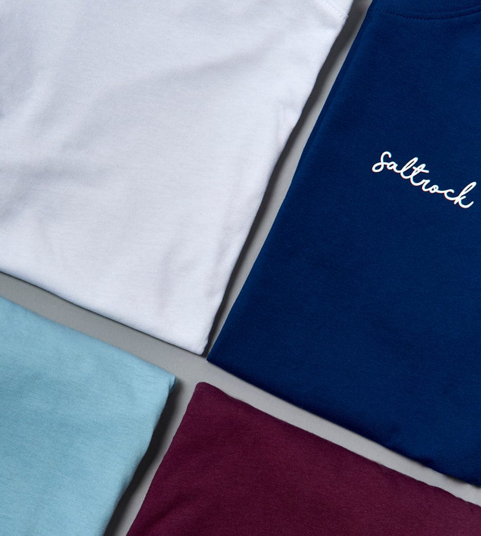 Four folded Velator crew fit t-shirts in different colors, one with the word "Saltrock" embroidered on it as branding, displayed on a flat surface.
