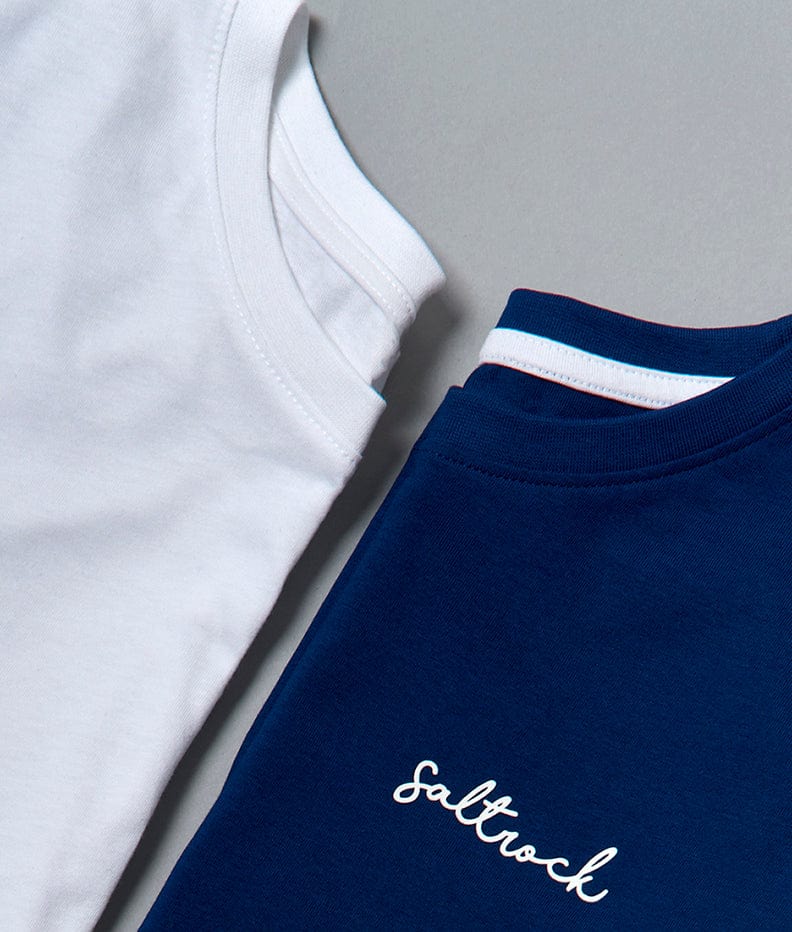 Two folded Velator t-shirts on a flat surface, one white and one navy blue with the word "Saltrock" written in cursive on the blue shirt, both featuring Saltrock branding.