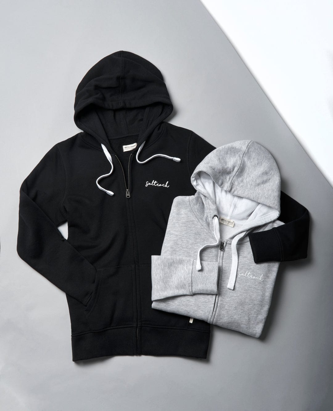 A black and grey Velator - Womens Zip Hoodie - Grey and a white hoodie with Saltrock branding make for staple wardrobe essentials.