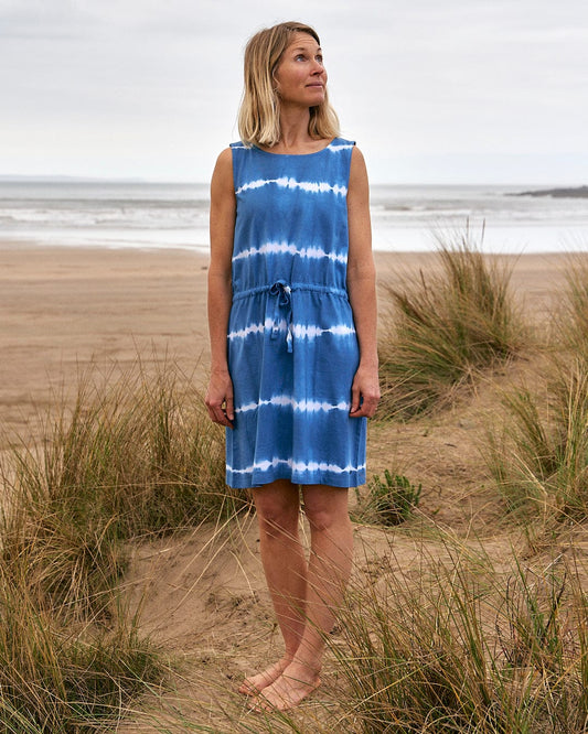 A woman standing on the beach in a Saltrock - Bauhaus Womens Tie Vest Dress - Blue, the perfect addition to her wardrobe.