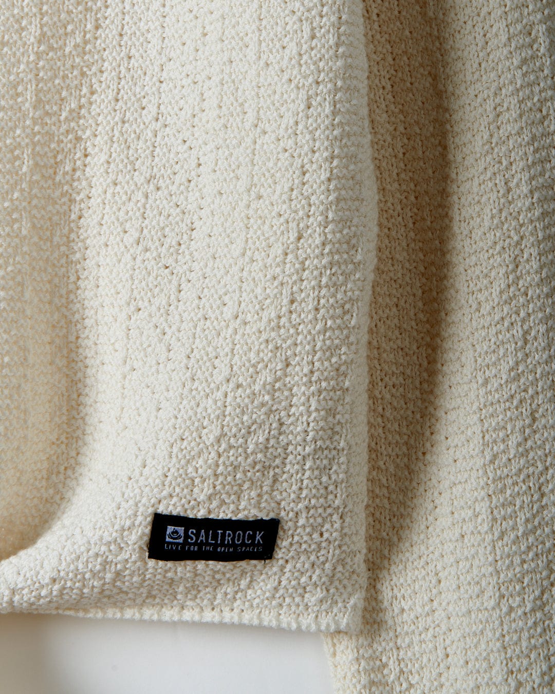 Close-up of a textured knit white towel with a black "Saltrock" label attached.