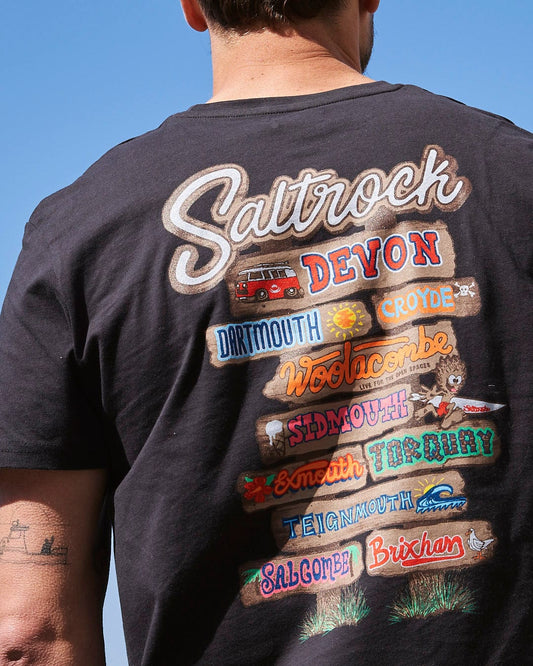 The back of a man wearing a t-shirt that says Saltrock - Beach Sign Devon Mens T-Shirt - Dark Grey.