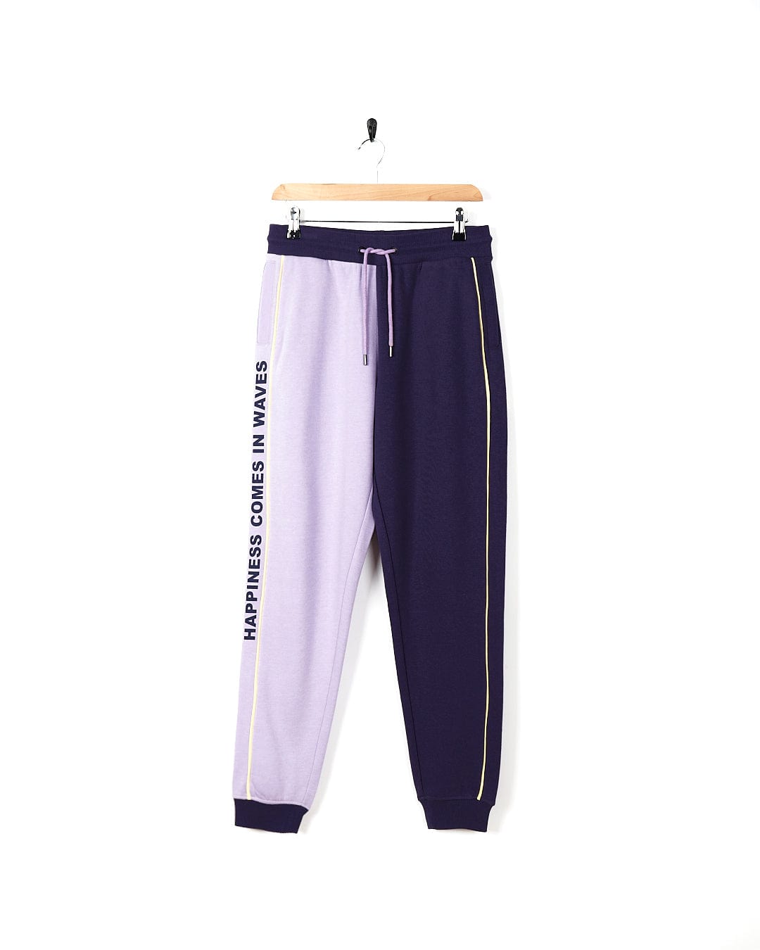 A pair of Betty - Womens Jogger - Light Purple sweatpants hanging on a hanger.