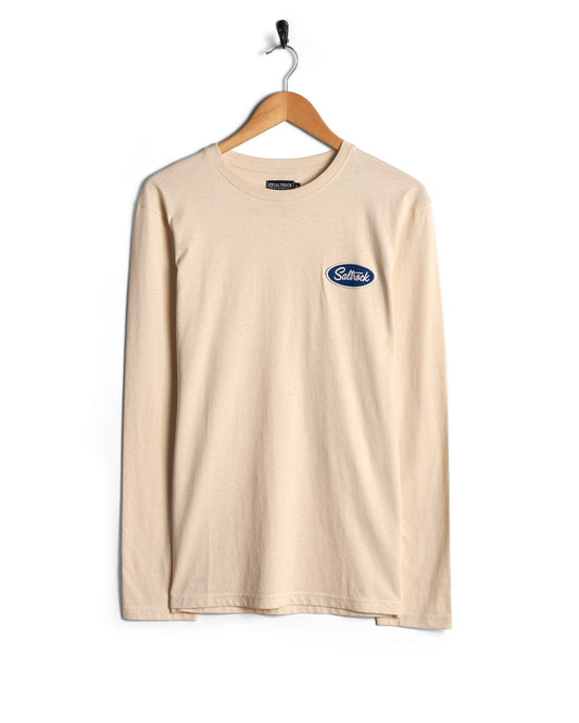 Cream long sleeve t-shirt with a small nylon Saltrock badge on the chest, hanging on a wooden hanger against a white background.