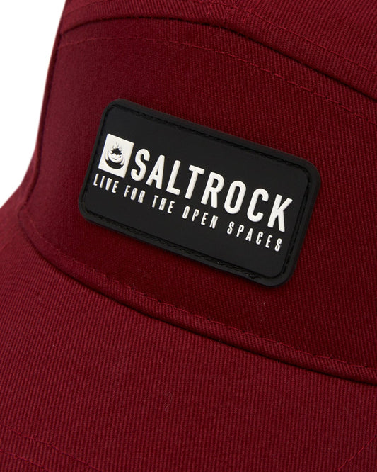 Close-up of a maroon cotton cap featuring a black "Saltrock - Life for the Open Spaces" logo patch, designed with an adjustable strap.