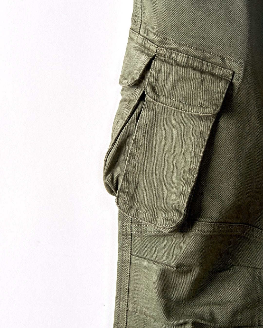Close-up of the flap and stitching details on a Bora Bora - Kids Trouser - Chino in Dark Green by Saltrock. The classic cargo style pocket stands out against the white background, highlighting its design.