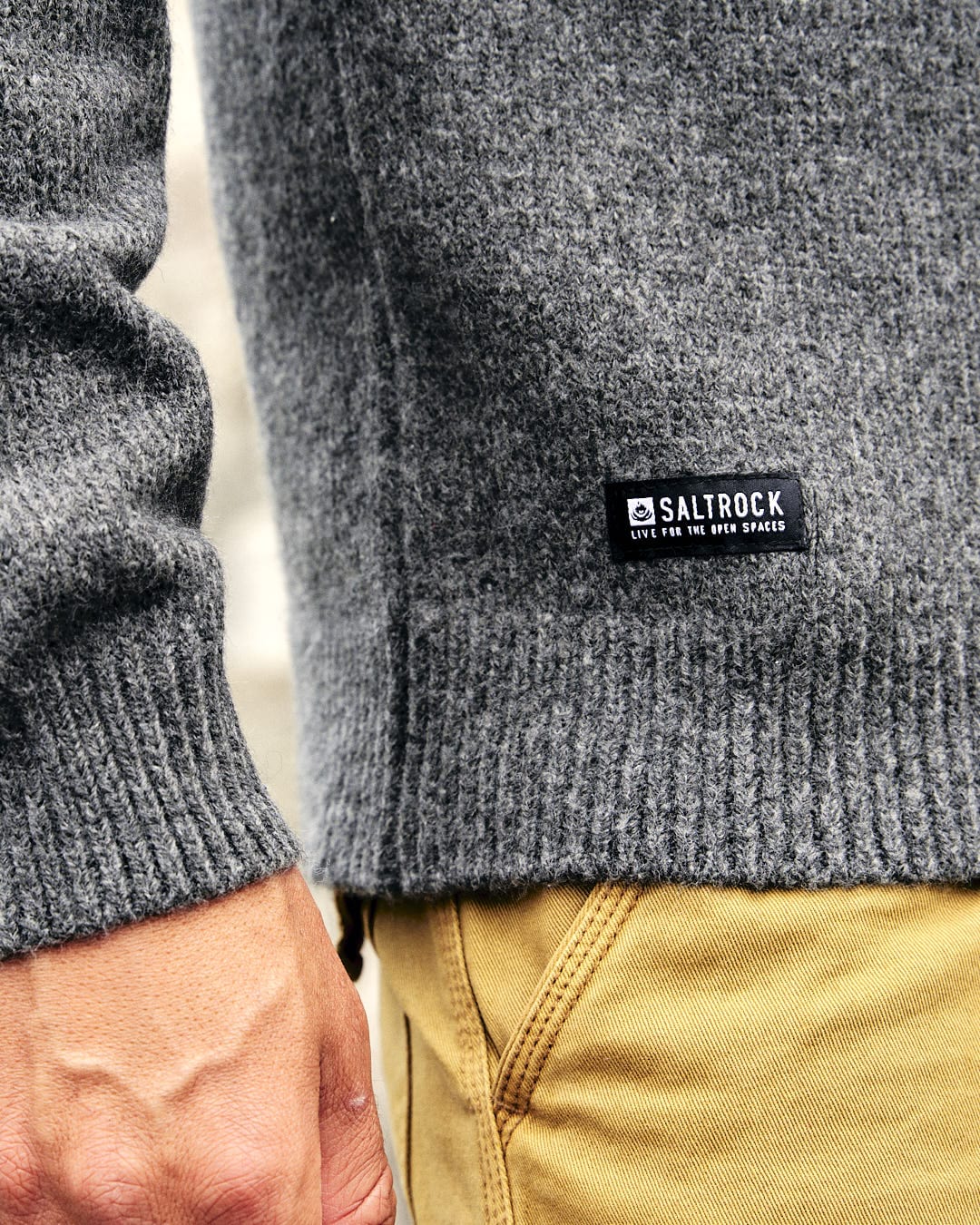 A man wearing a Saltrock Bowen Mens Knitted Crew sweater in a grey color paired with khaki pants.