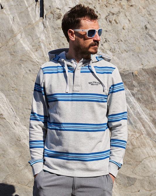 A man wearing a Saltrock Byron - Mens Pop Hoodie - Grey in front of a rock.