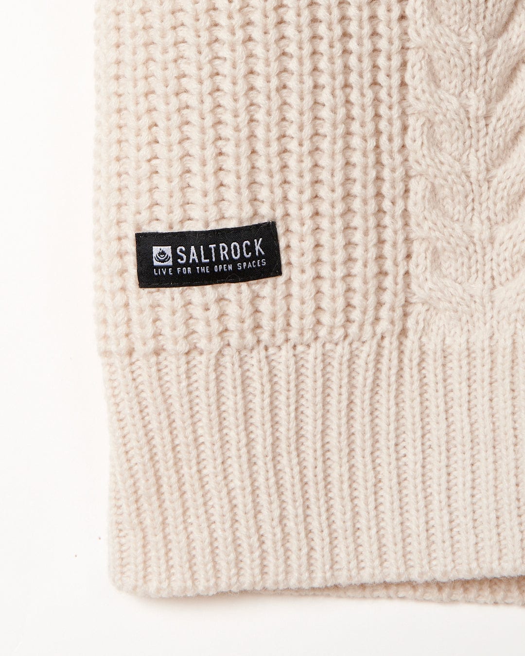 Close-up of a cream-colored cable knit fabric with a Saltrock Women's Knitted Longline Cardigan - Cream label.
