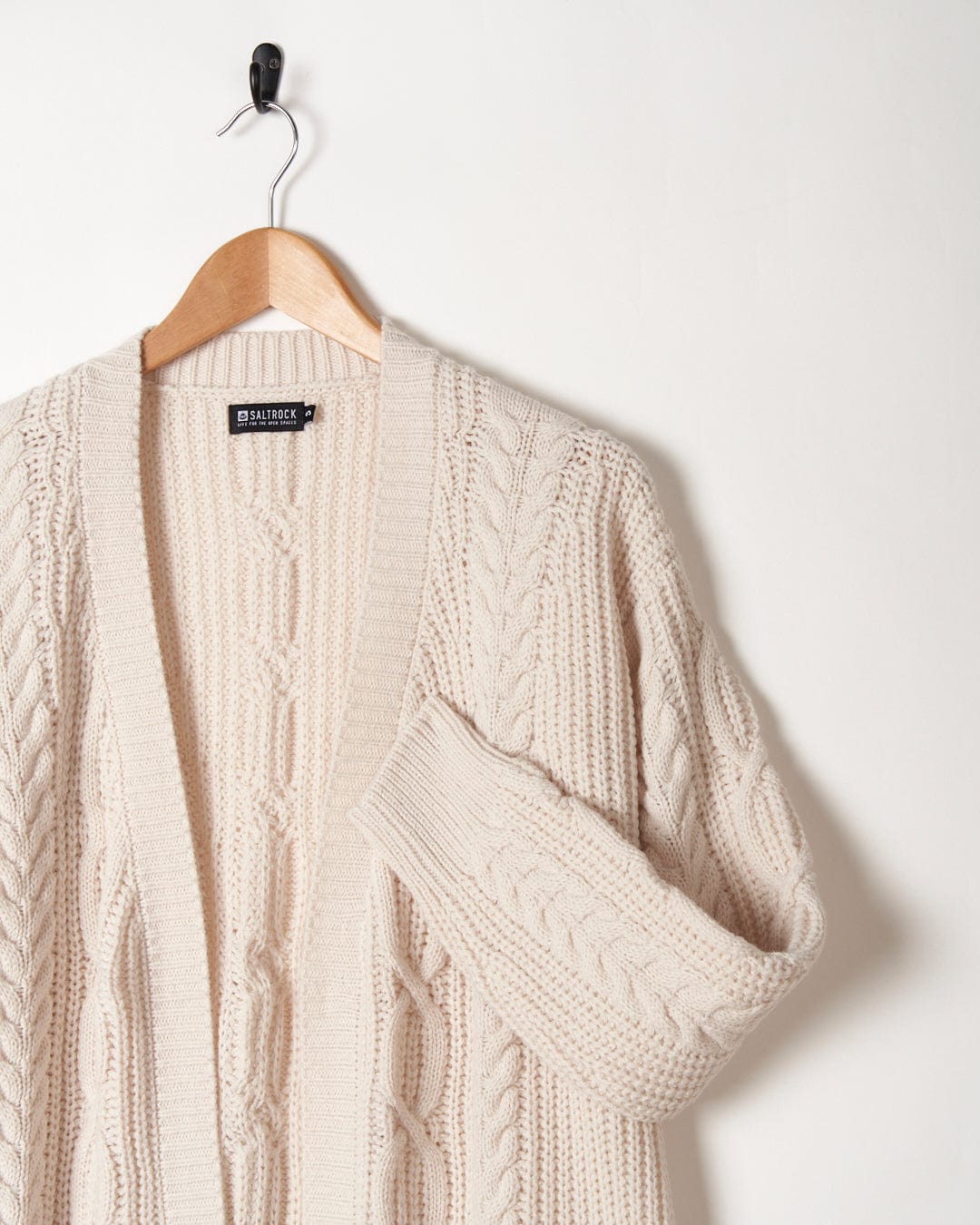 Saltrock Cream open-front cable-knit cardigan hanging on a coat hanger against a white background.