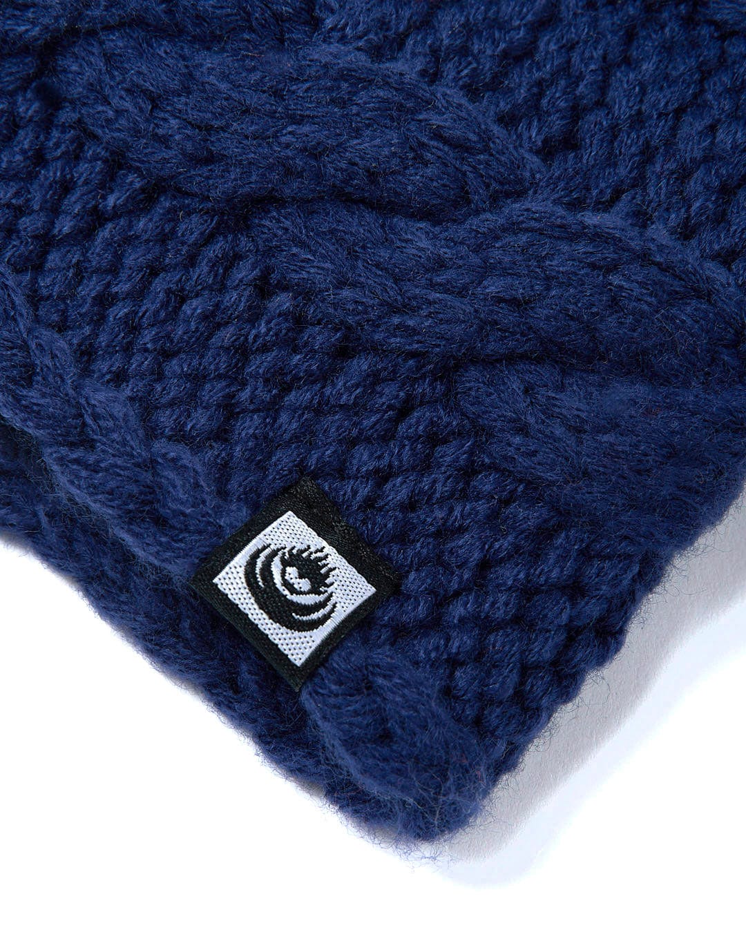A fashionable Saltrock Cable - Knitted Headband - Blue with a logo on it, offering both warmth and style.