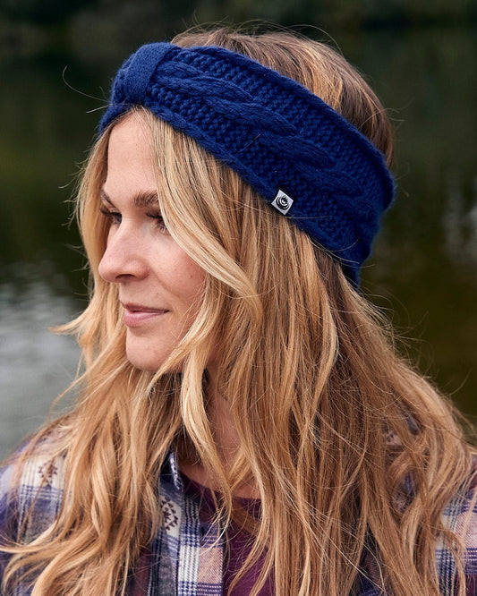 A fashionable woman sporting a warm Saltrock Cable - Knitted Headband - Blue.