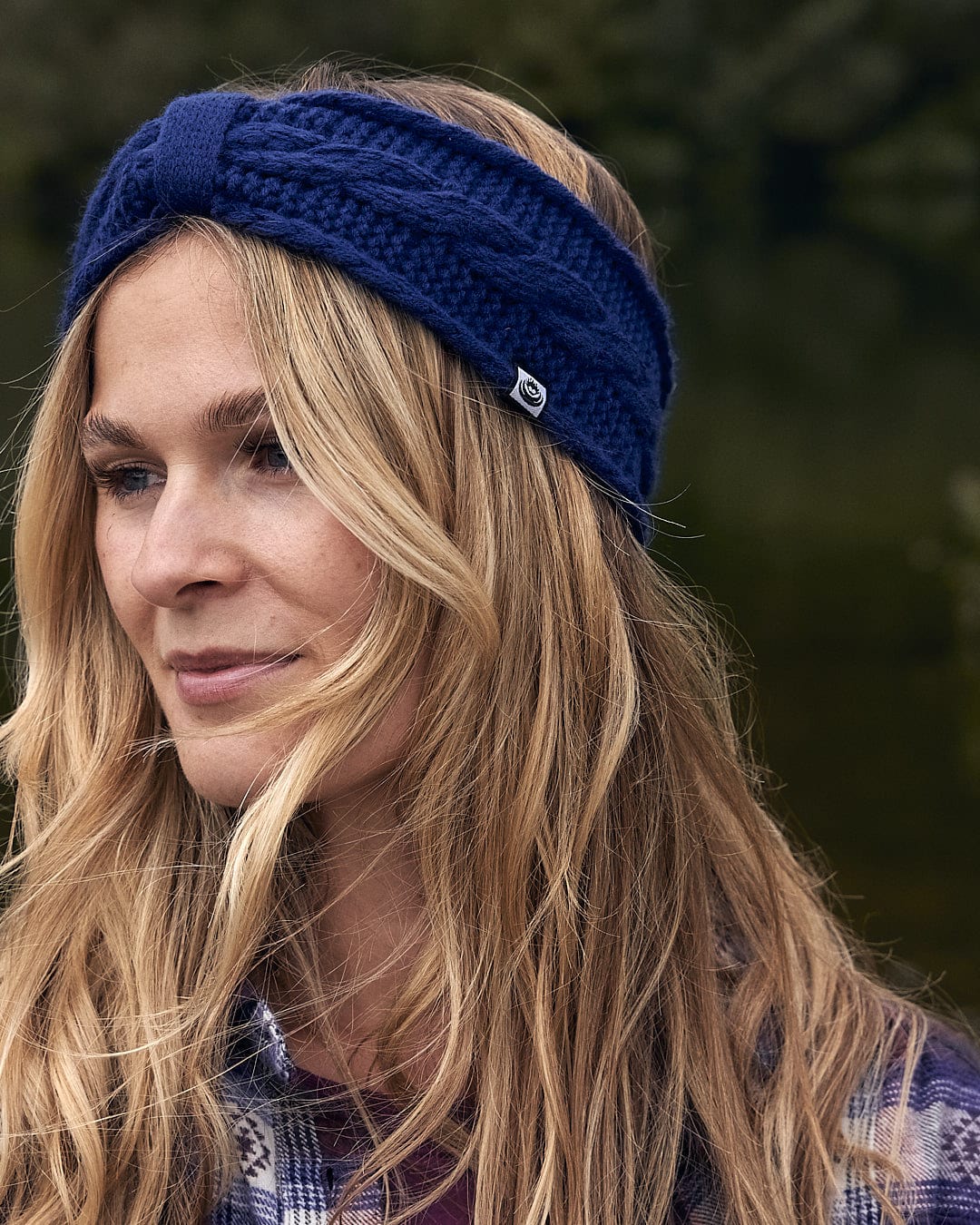 A fashion-forward woman donning a cozy Saltrock Cable - Knitted Headband - Blue, showcasing her warmth and style.