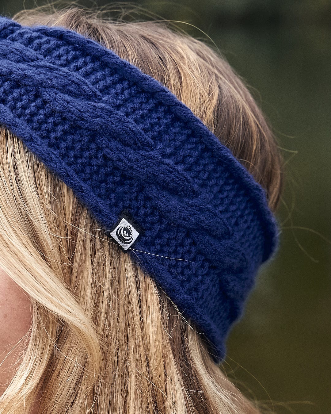 A fashionable woman wearing a Saltrock Cable - Knitted Headband - Blue for warmth.