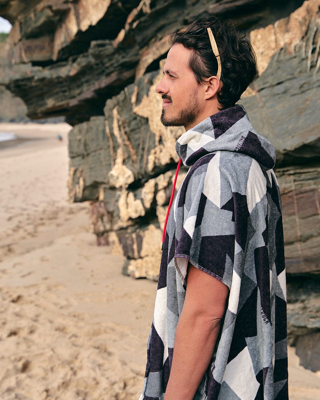 A man wearing the Geo Camo - Changing Towel - Grey by Saltrock on the beach.