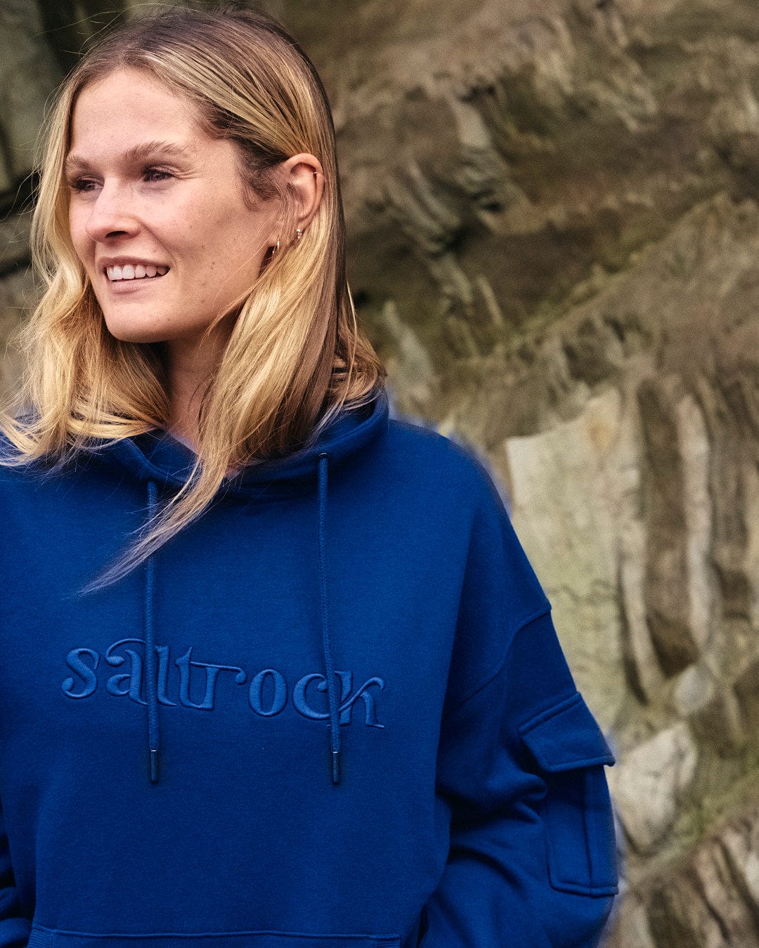 A woman wearing a blue Celeste - Womens Pop Hoodie - Blue with an embroidered Saltrock branding and a drawstring hood.