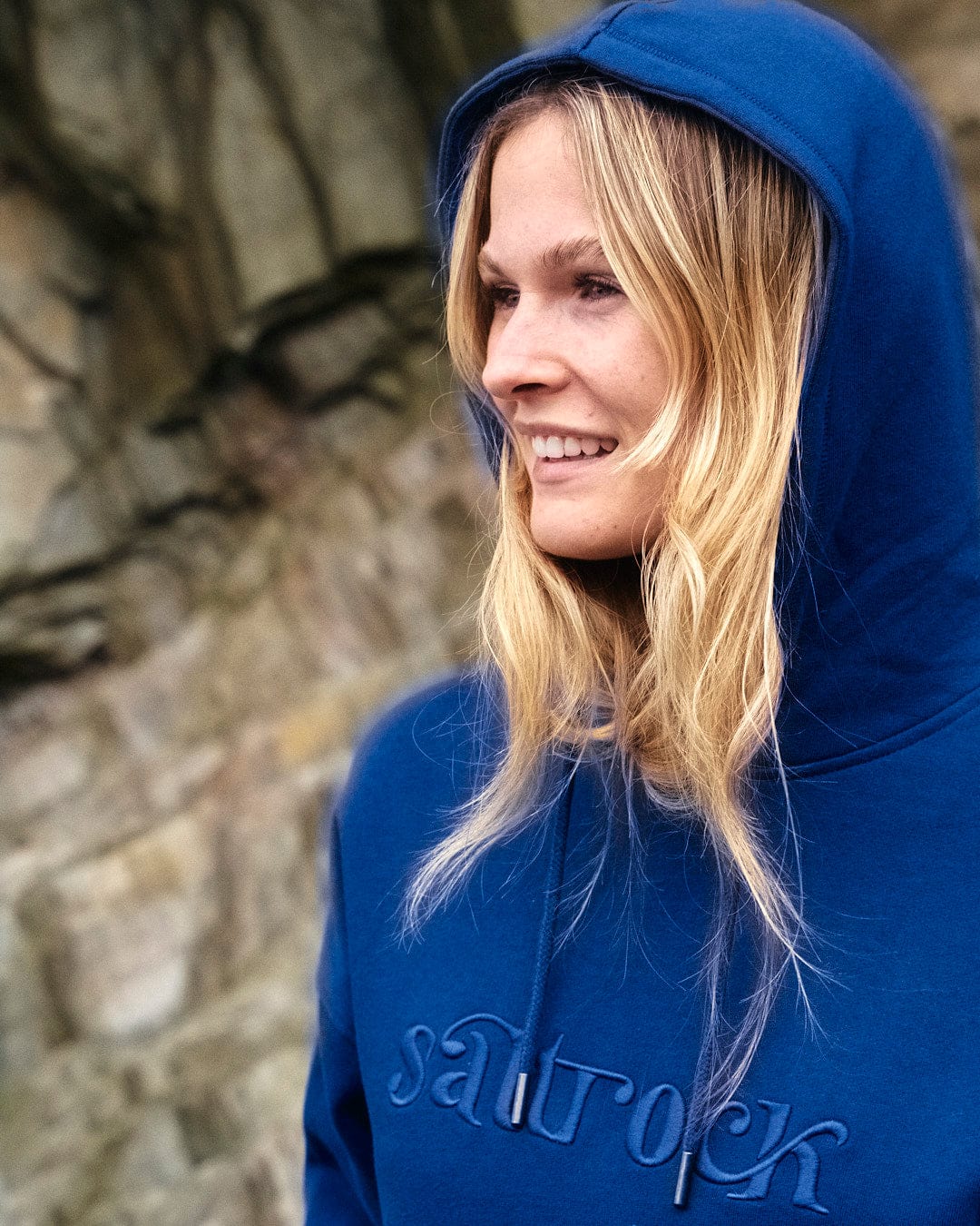 A young woman with Saltrock branding, wearing the Celeste - Womens Pop Hoodie - Blue with a drawstring hood.