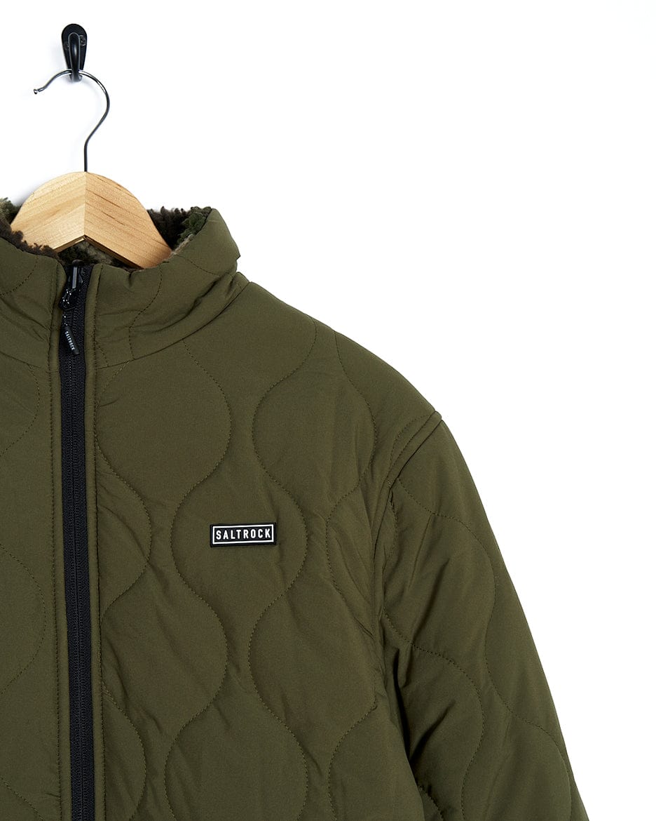 A Saltrock Cirrus - Quilted Reversible Jacket - Dark Green hanging on a hanger.