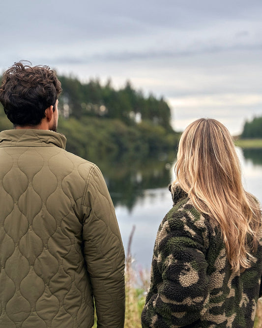 A man and woman in Saltrock Cirrus - Quilted Reversible Jackets - Dark Green looking at a lake.