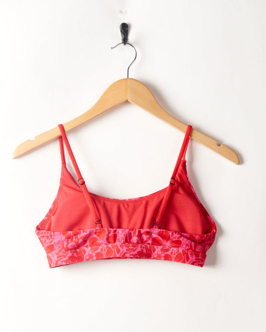 Cleo Hibiscus - Recycled Bikini Top - Pink by Saltrock hanging on a wooden hanger against a white background.