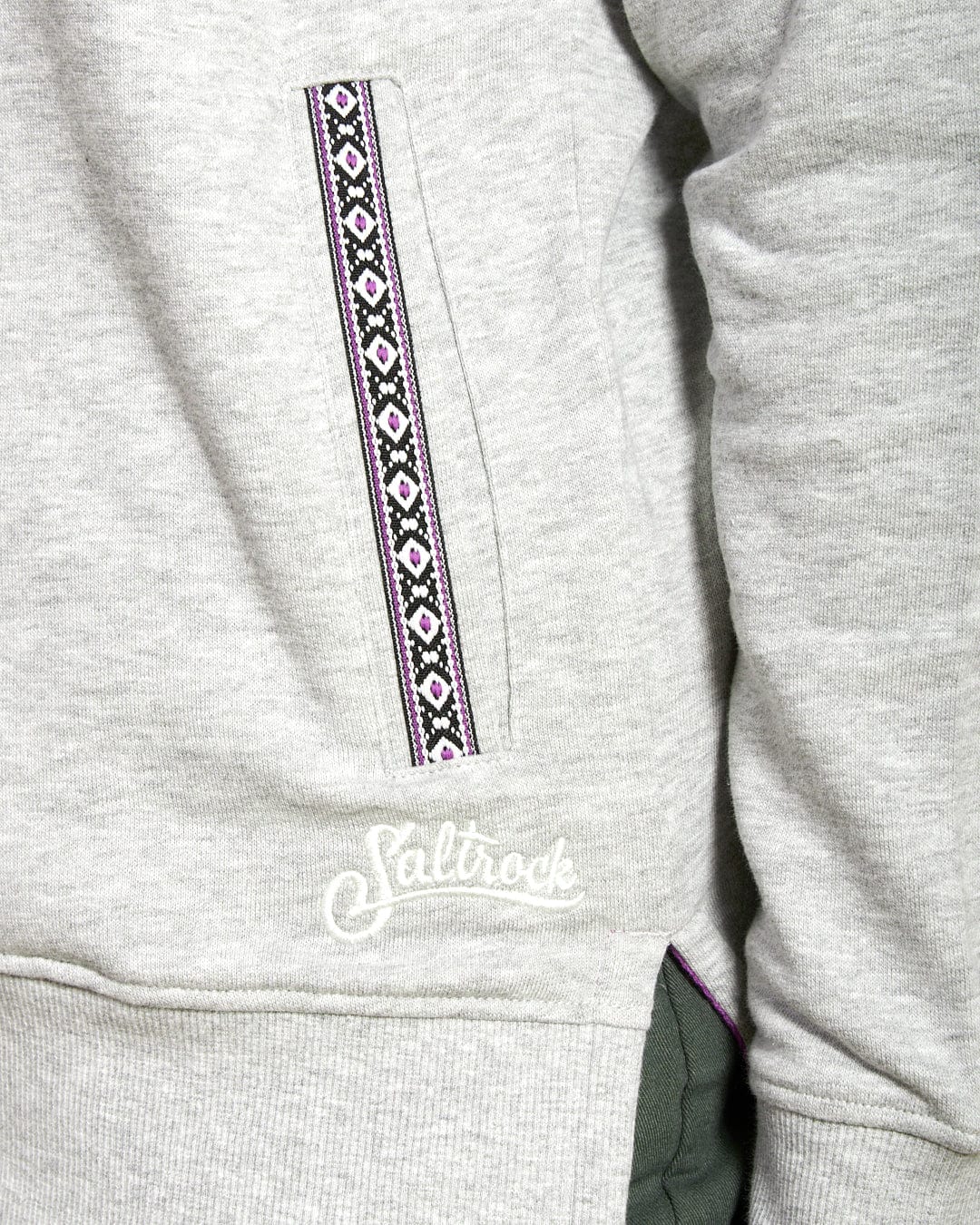 Close-up of the Saltrock Cliffden Women's Pop Hoodie in grey, featuring a patterned zipper, branded embroidery near the pocket, visible green lining, and stylish cotton fabric that's machine washable.