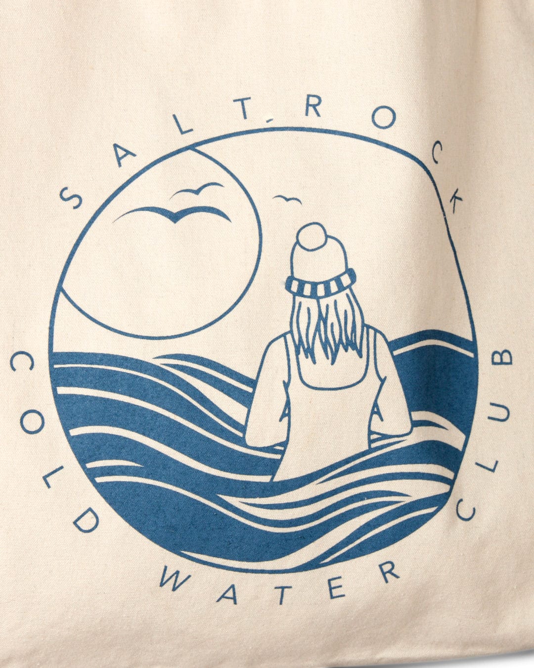 Graphic print on canvas material of a person in water with waves, the sun, and the words "Saltrock Cold Water Club" on a Saltrock Cold Water Club - Recycled Shopper Bag - Cream.