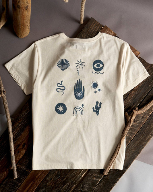A Journey - Recycled Womens Short Sleeve T-Shirt in Cream with various black embroidered graphics including shells, palm trees, and abstract designs, displayed on a wooden frame by Saltrock.