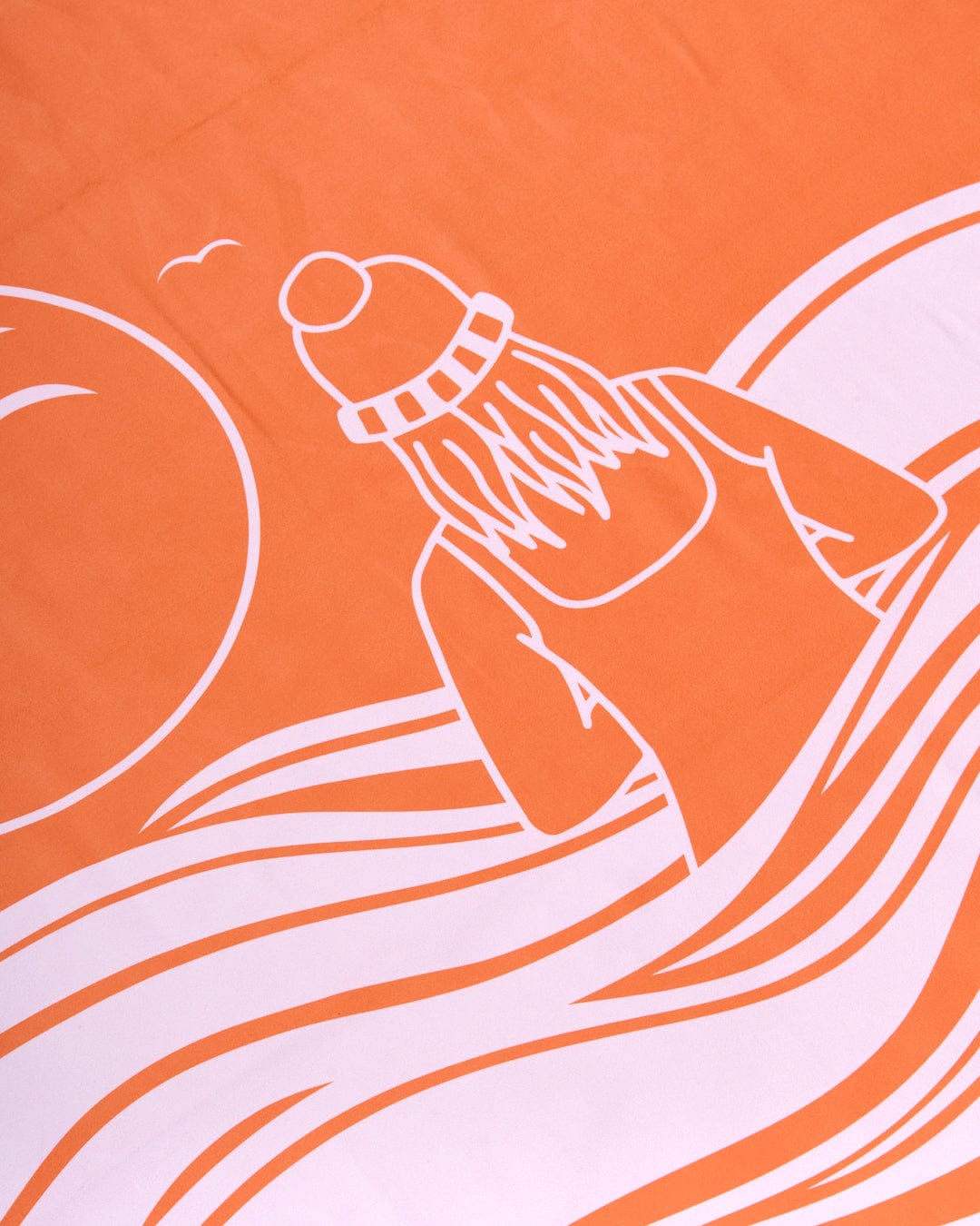 An absorbent Saltrock orange towel with a drawing of a woman riding a surfboard.