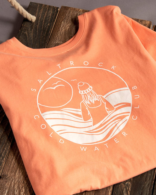 An orange cotton Coldwater Club T-shirt with a graphic image of a surfer on it.