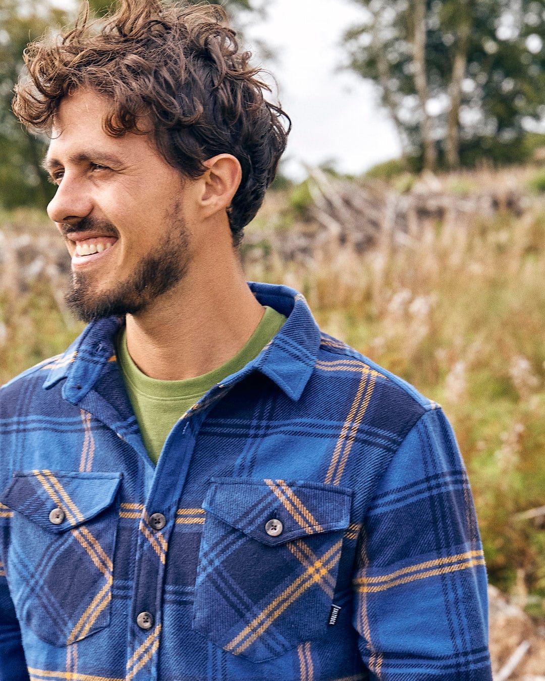 A man wearing a Colter - Mens Hooded Longsleeve Shirt - Dark Blue by Saltrock standing in a field.