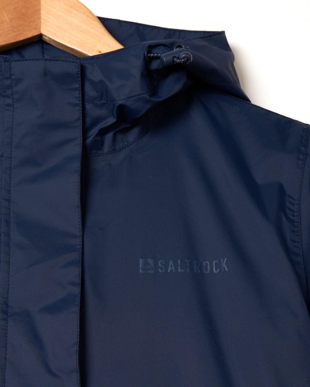 A close-up of a Saltrock Cooper womens packable waterproof jacket in dark blue, with focus on the collar and a visible adjustment toggle.