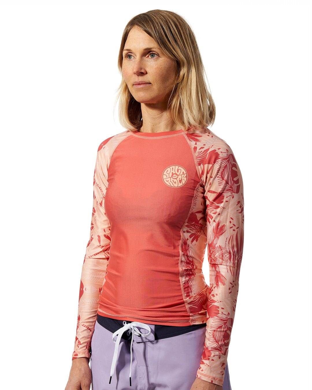 A woman wearing a Coraline - Womens Long Sleeve Rashvest - Coral from Saltrock.