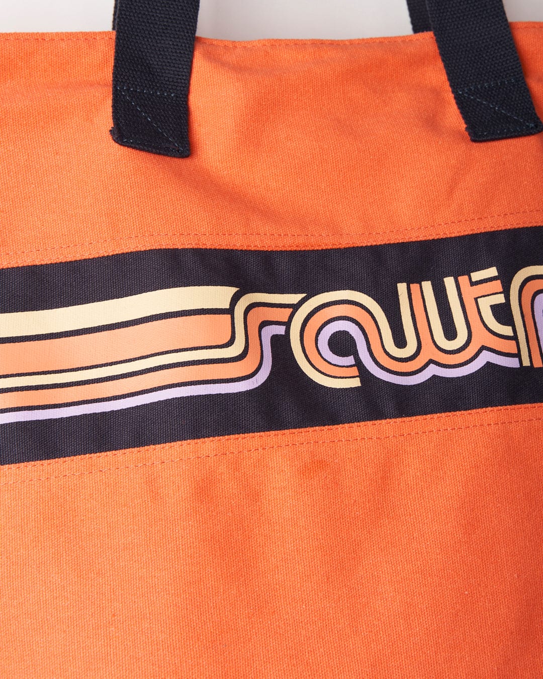Close-up of a Cora Retro Beach Bag - Coral with a durable material and a striped Saltrock logo design.