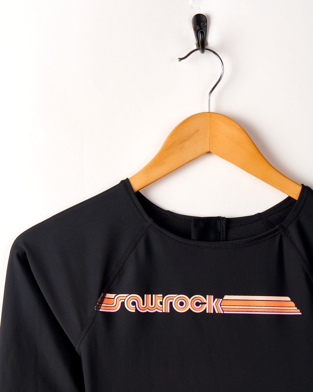 Dark Grey long sleeve swimsuit with "Cora Retro" text in white and orange on a wooden hanger against a white background. (Saltrock)