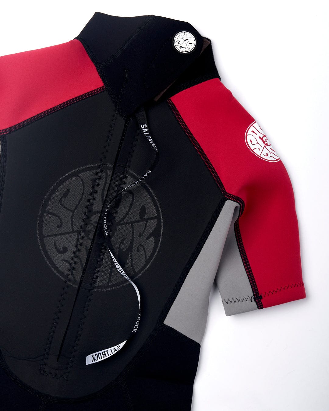 A red and black neoprene wetsuit with a YKK zippered front and logo patches on the shoulders laid flat on a white background. - Saltrock Core - Boys 3/2 Shortie Wetsuit - Black/Red