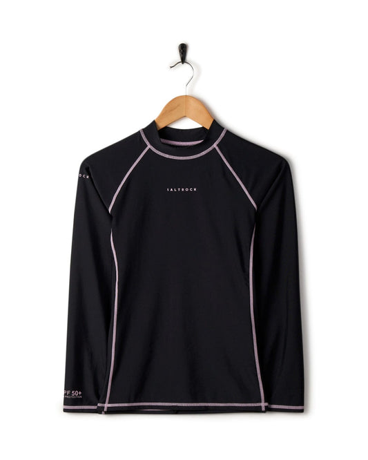 Black long-sleeve sports shirt with white and pink trim, featuring UPF 50 protection, displayed on a hanger against a white background. - Core - Recycled Womens Long Sleeve Rashvest in Black by Saltrock.