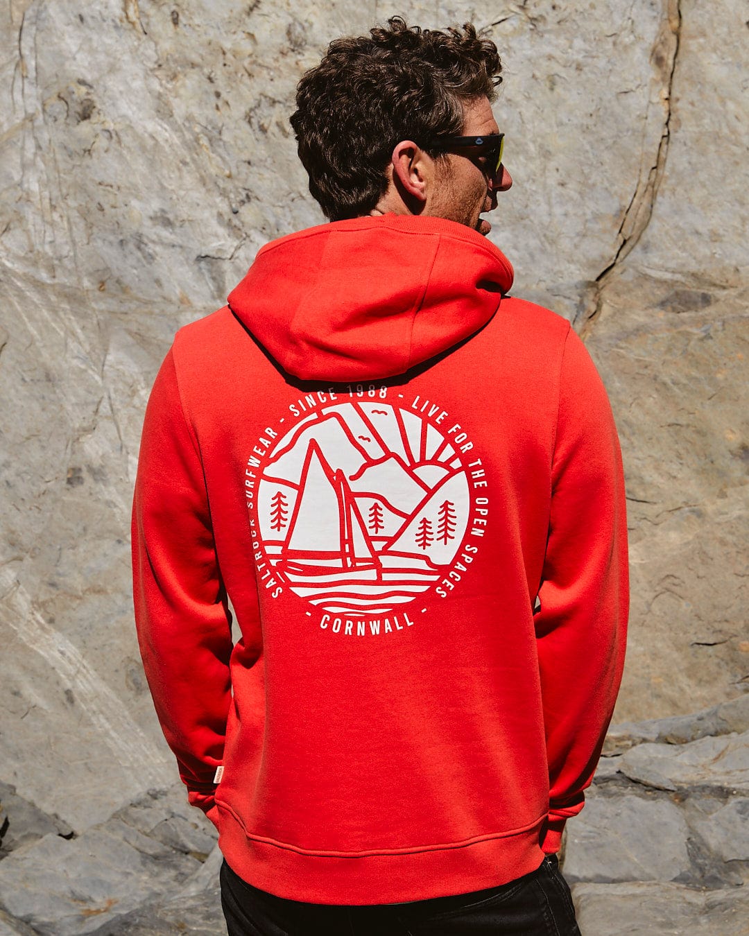 The back of a man wearing a Cornwall Sailaway - Mens Pop Hoodie - Red by Saltrock.