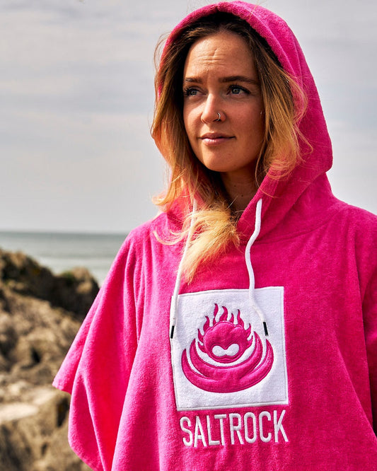 Woman wearing a Saltrock Corp Changing Towel - Bright Pink on a beach.