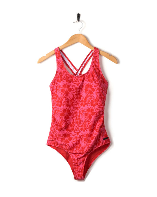 Corrine Hibiscus-print swimsuit hanging on a wooden hanger against a white background.