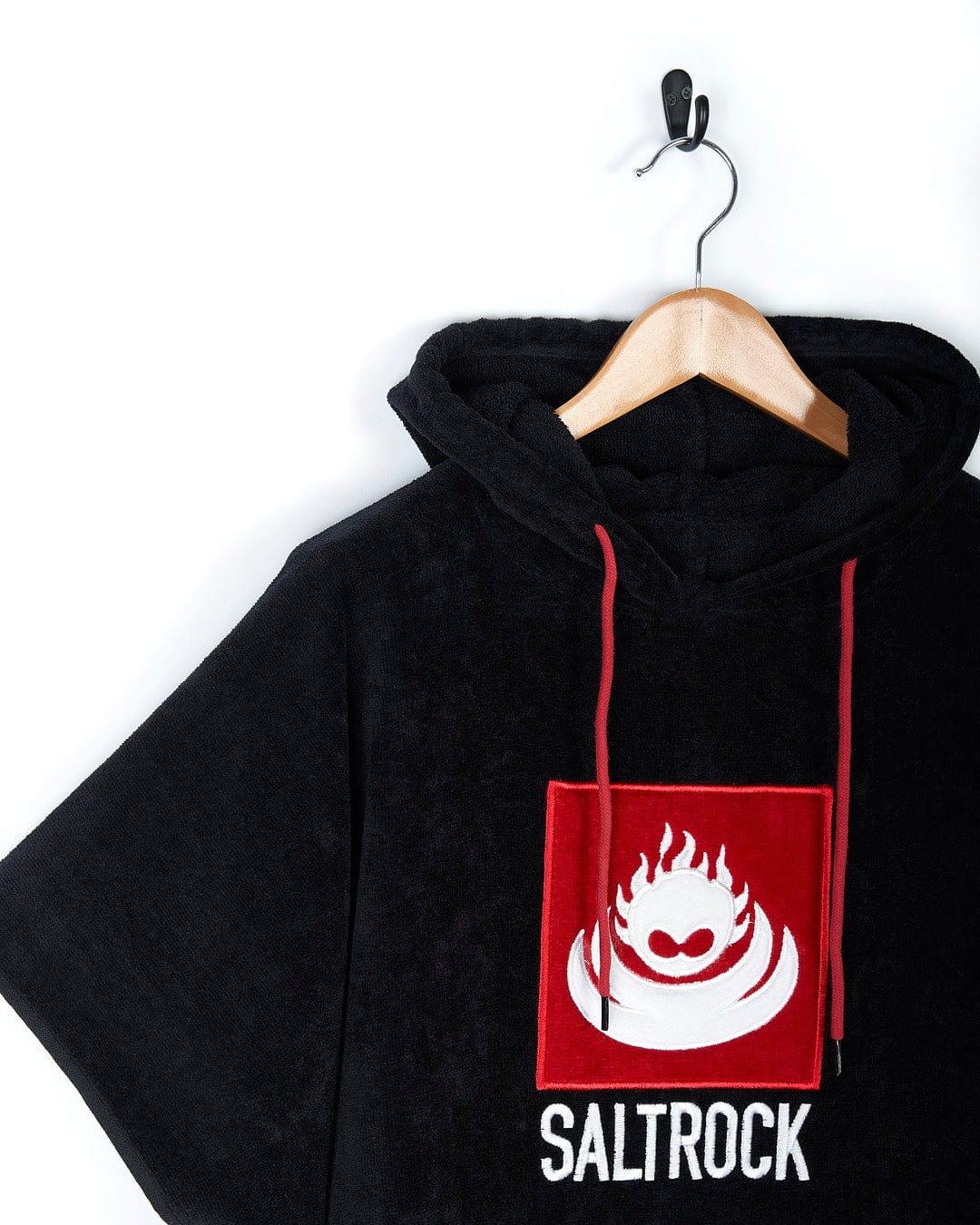 A black hoodie with the word Corp - Changing Towel - Black/Red on it, made by Saltrock.