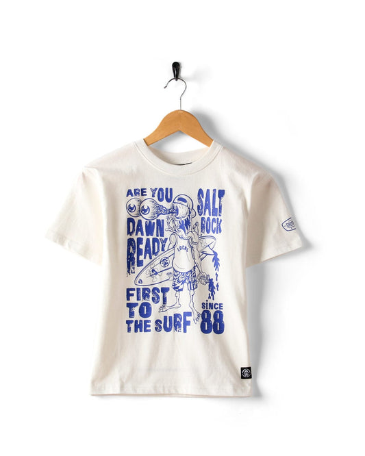 The Saltrock Dawn Ready Kids T-Shirt in white features blue surf-inspired graphics and phrases like “Are you dawn ready?” and “Salt Rock, first to the surf since ‘88.” Made from 100% cotton and machine washable.
