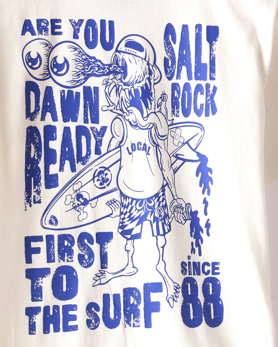 The Dawn Ready Kids T-Shirt by Saltrock features a surfer with two-eyed sunglasses and a flaming mouth, bold blue text, classic Saltrock branding since 1988. Made from 100% cotton and machine washable for easy care.